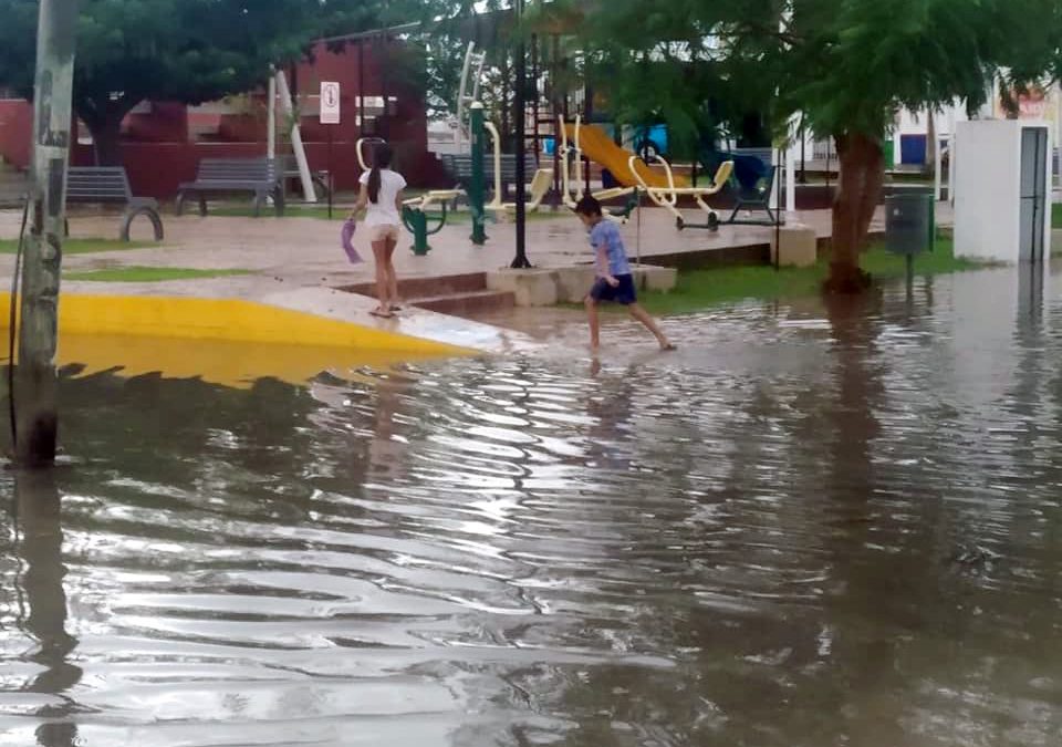 Niños cruzando el parque inundado después de la lluvia de esta tarde. Vecinos señalan serias deficiencias en las recientes remodelaciones.