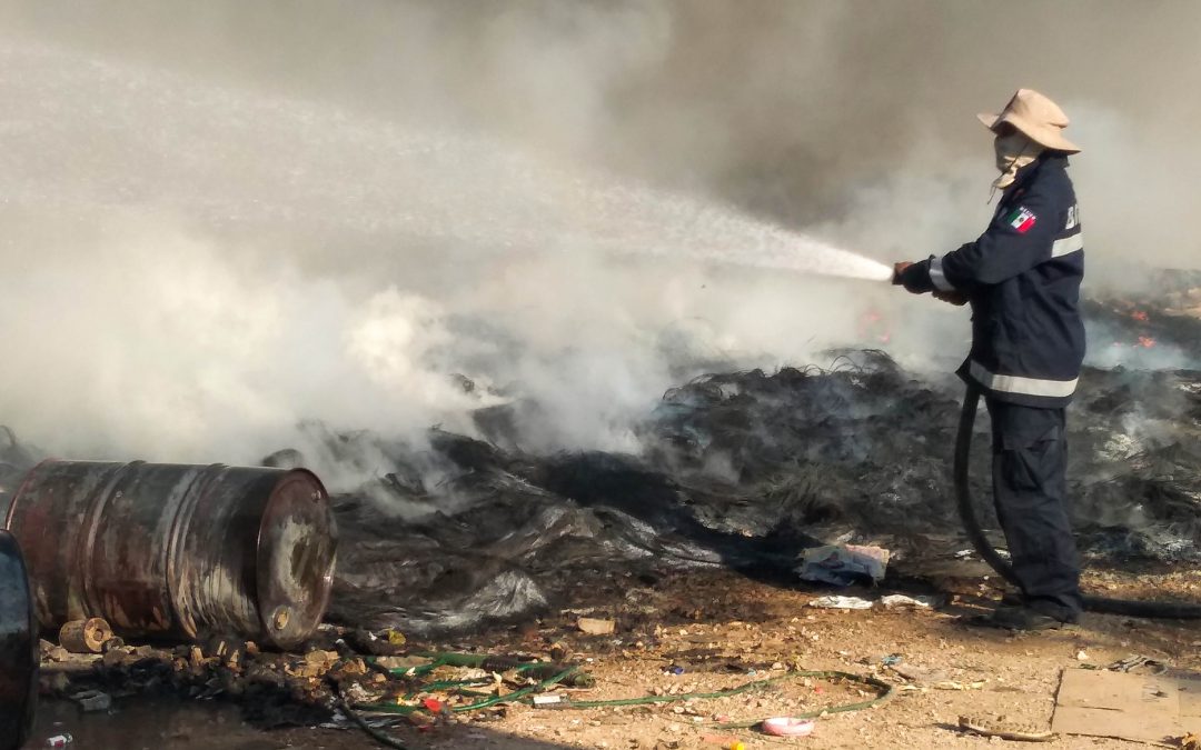 Un bombero de la SSP dispara su chorro de agua sobre una pila de llantas consumidas por el fuego en el basurero municipal de Valladolid, en Yucatán, México.