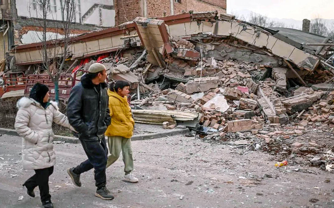 Habitantes de la provincia de Gansu observan los escombros de un edificio derrumbado a consecuencia del sismo de 6.2 grados en la escala de Richter.